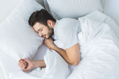 Man sleeping on white sheets peacefully.