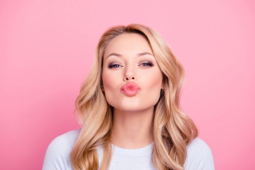 Woman pouting with pink glossy lips.