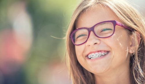 Young girl with spectacles and braces laughing.