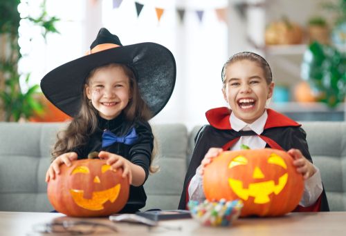Happy Children on Halloween holding carved pumpkins.
