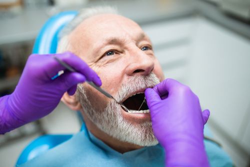 Old man getting a dental treatment at the dentist's office.