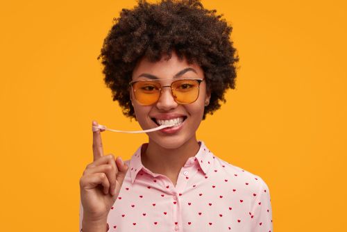 Cheerful African woman with glasses chewing gum.