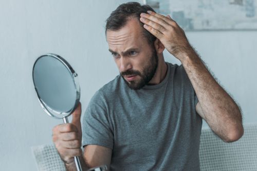 Man examining his hair loss in a mirror.