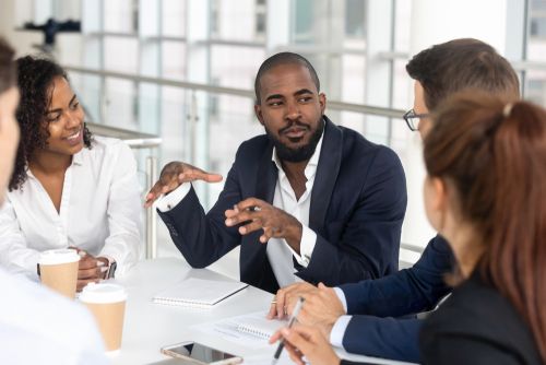 Black man talking to his millennial office peers.  