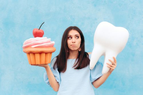 Woman holding a giant cupcake and a tooth model.