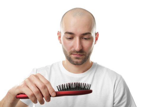 Sad bald man staring at a brush.