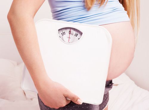 Pregnant woman carrying a weighing scale. 