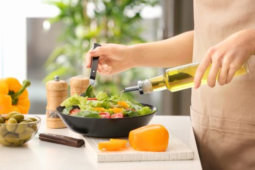 Woman drizzling olive oil on her salad. 
