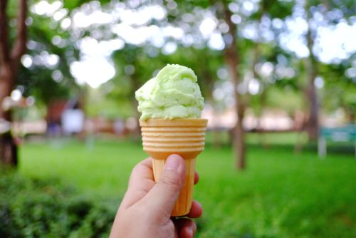 Woman holding pistachio ice-cream in the park.