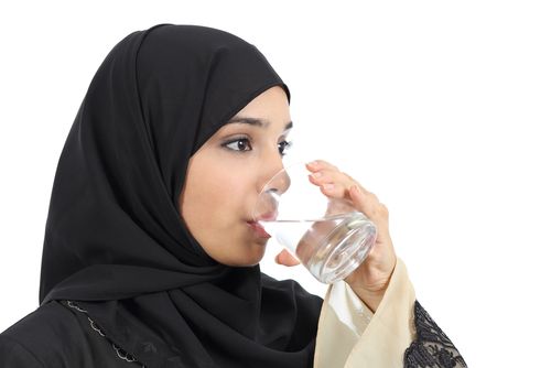 Woman in hijab drinking water.