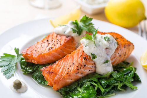 Grilled salmon with white sauce and veggies.