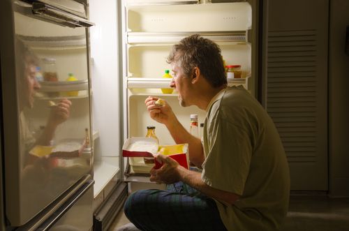 Man suffering from insomnia indulging in late night snacks.