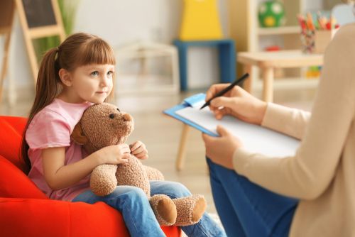 A young girl with her teddy bear at the psychologist's clinic.