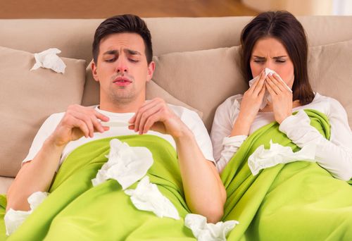 Sick husband and wife covered in tissues.