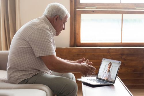 An elderly patient talking to his doctor from the ease of his home.